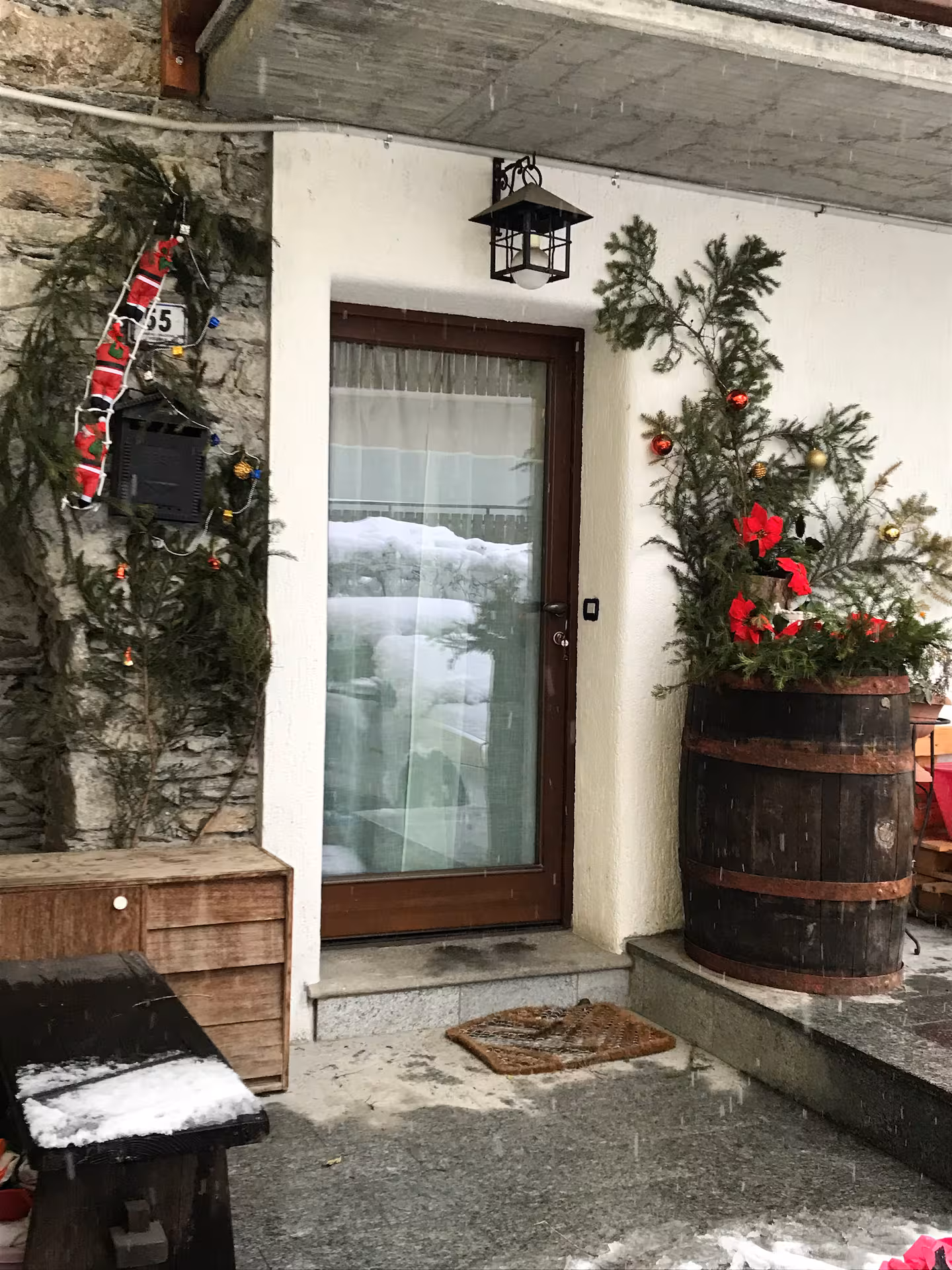 Exterior entrance door in winter with festive plants, barrel planter and lantern